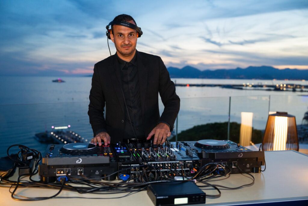 DJ Brice Adel aux platines au crépuscule sur le rooftop du JW Marriott à Cannes, TFWA 2026