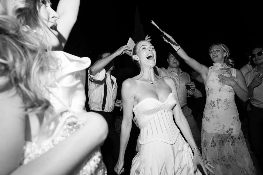Christy danse et rit aux éclats entourée de ses invités pendant la soirée de son mariage à Capelongue, Bonnieux